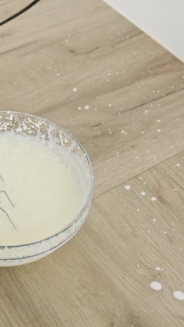 vertical shot of mixing tiramisu cream with drops spilling onto the table, cleaned up promptly