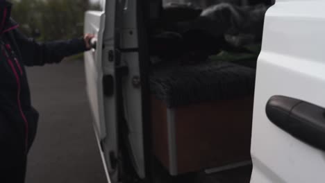 woman opening the back door of a 4x4 vehicle rebuilt as a campervan