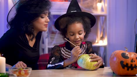 mother and daughter carving pumpkins for halloween