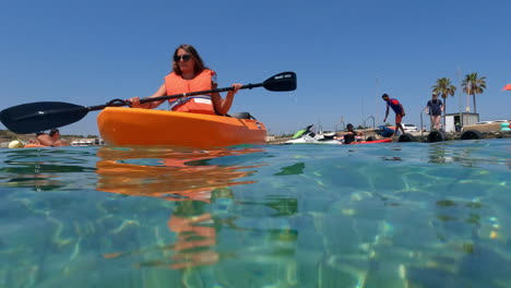 close up of a young lady paddling past with her orange kayak