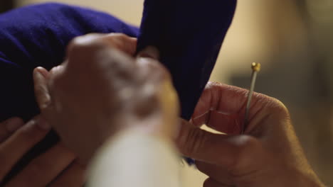 close up studio shot of senior sikh man helping younger sikh man to tie fabric for turban against plain background shot in real time 1