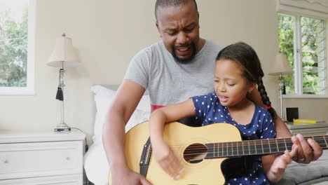 father and daughter playing guitar in bedroom 4k