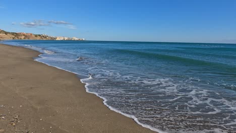 gently crashing waves spread white wash along sandy shore as water recedes