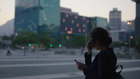 beautiful portrait of young business woman student waiting on urban city street using smartphone texting browsing