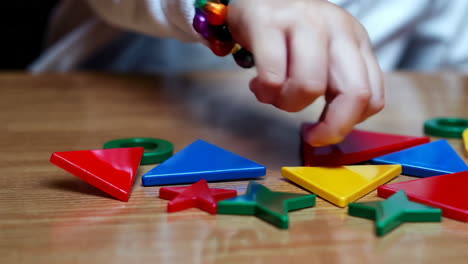 child's hand engaged in play with colorful geometric shape toys
