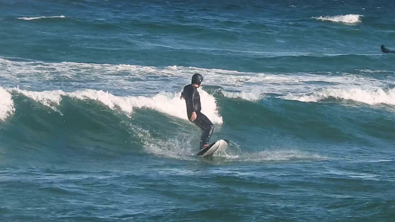 A pump foil surfer rides the waves with skill, but eventually succumbs to the water's embrace as the ride comes to an end, showcasing the dynamic nature of the sport