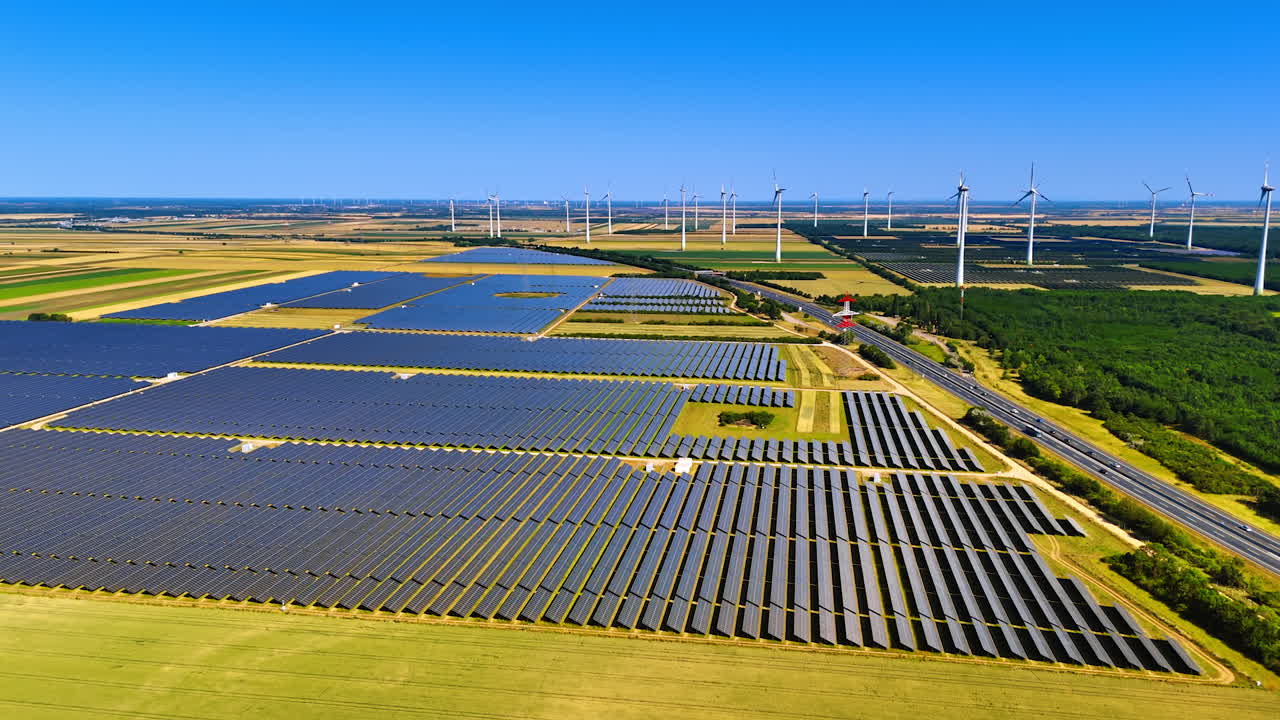 Renewable energy solar and wind. Vast fields filled with solar panels and wind turbines under a clear blue sky demonstrate renewable energy production