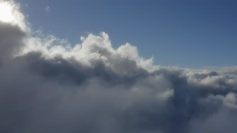 sunlight diffuses light between thick white fluffy cloudscape texture, aerial dolly