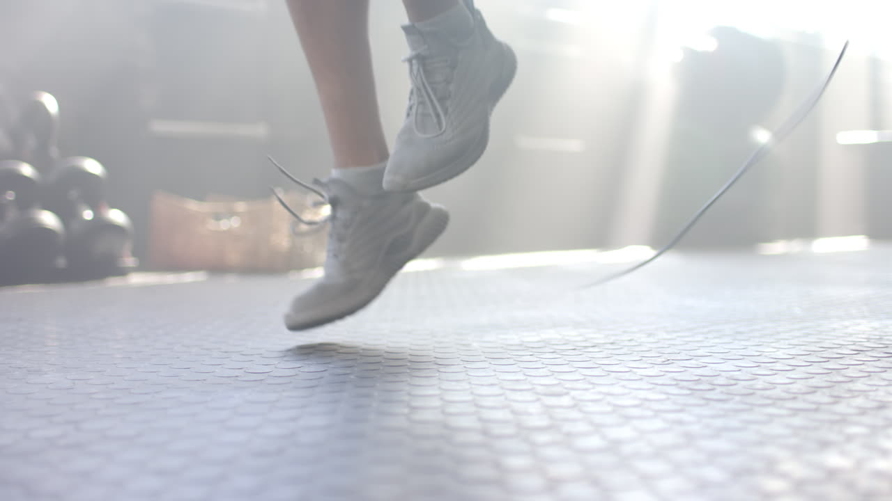 Jumping in white sneakers, man exercising in gym with sunlight streaming in