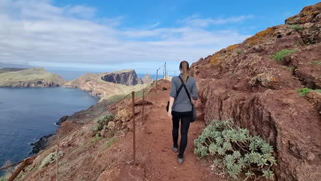 toma cinematográfica de una mujer caminando por los senderos que llegan a la punta de san lorenzo en la isla de madeira y en un día soleado