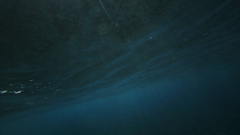 moody grey rubble coral reef with ocean water glistening and shining as wave creates barrel, view from behind