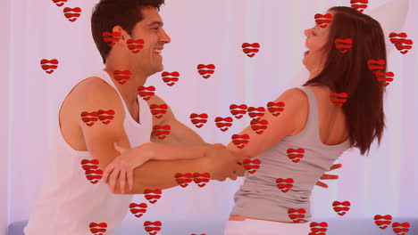 animación de iconos de corazón sobre la lucha de almohadas de una pareja caucásica