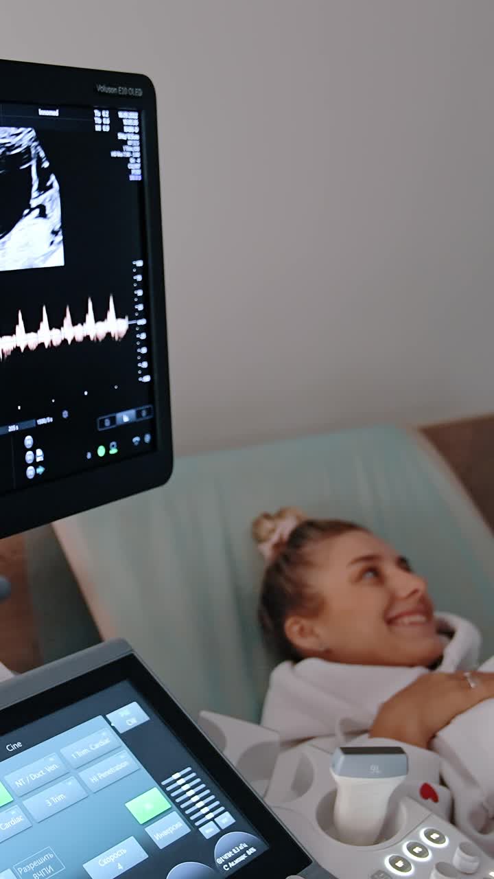 Monitor of ultrasound machine shows the baby image in mom's abdomen. Expecting couple at ultrasonic check up. Vertical video