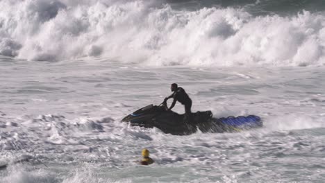Camera-chasing-a-jet-ski-driver-who-fights-the-waves-and-a-surfer-who-can't-escape-the-foaming-waves