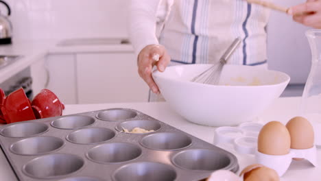 mujer poniendo masa en el molde de muffin