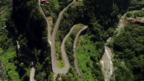 drone footage of curvy steep road in the green mountains on sunny day