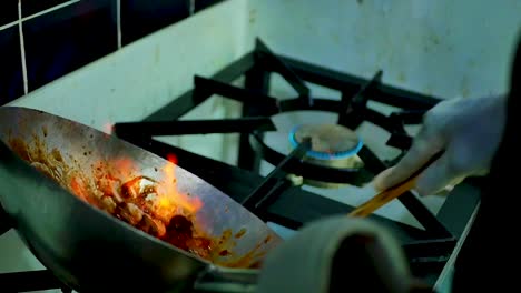 chef cooking stir-fry in a wok with flaming fire