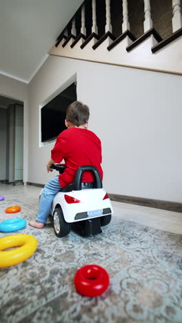 lovely toddler boy wearing sunglasses rides a toy car. kid riding among the toy pyramid rings. low angle view. vertical video.