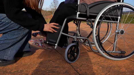 granddaughter helping her grandmother place her feet in the wheelchair