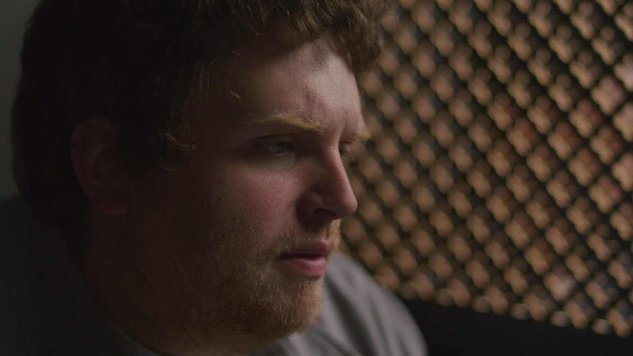 Young Reflective Man Talking beside Lattice Screen in Confessional