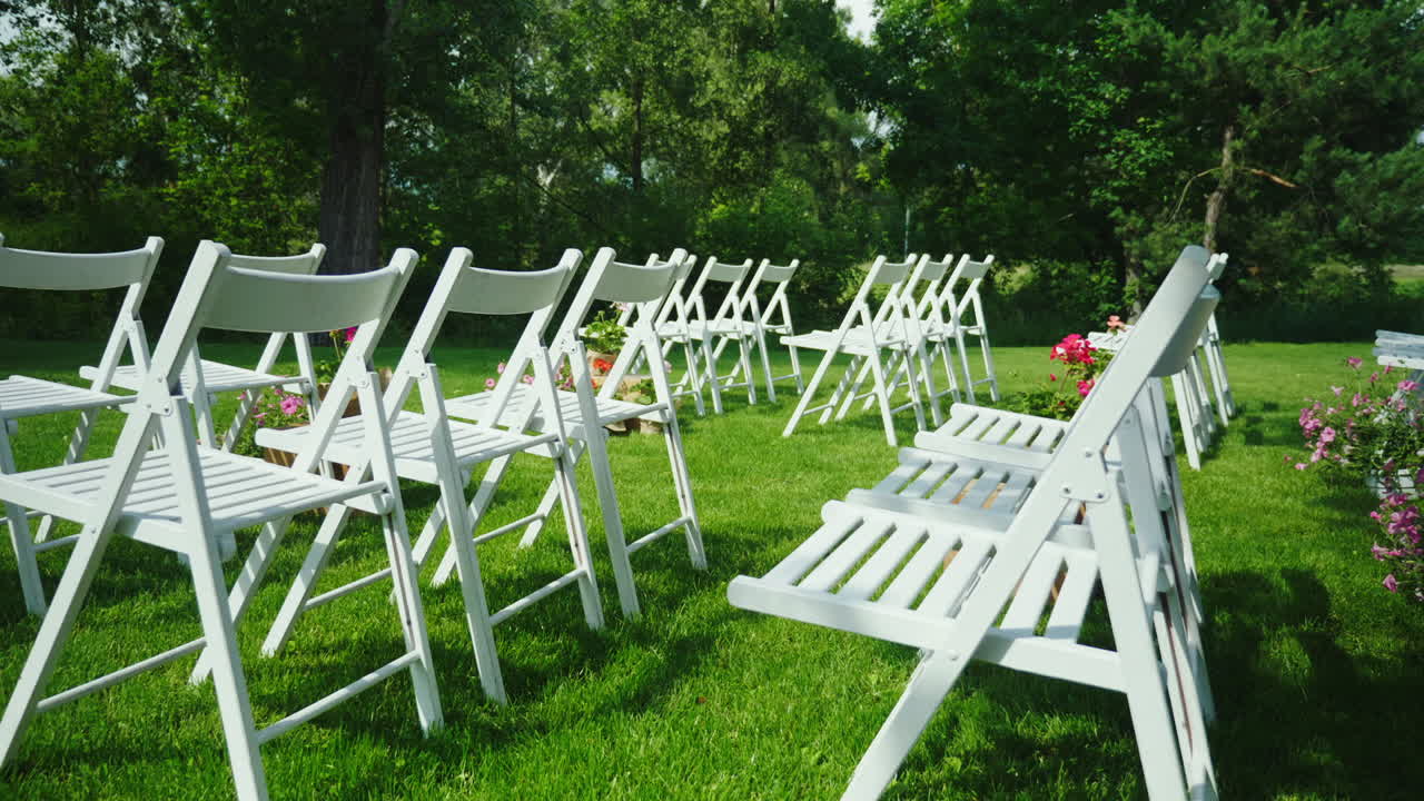 결혼식을 위한 흰색 나무 의자가 줄지어 있는 녹색 잔디밭