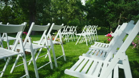 green lawn with rows of white wooden chairs place for the wedding ceremony