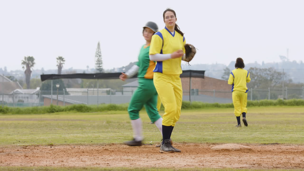 Multiracial female baseball players, catching and throwing the ball, running on a pitch