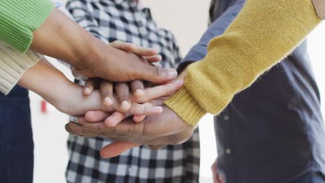 diverse male and female business colleagues stacking hand and motivating in office