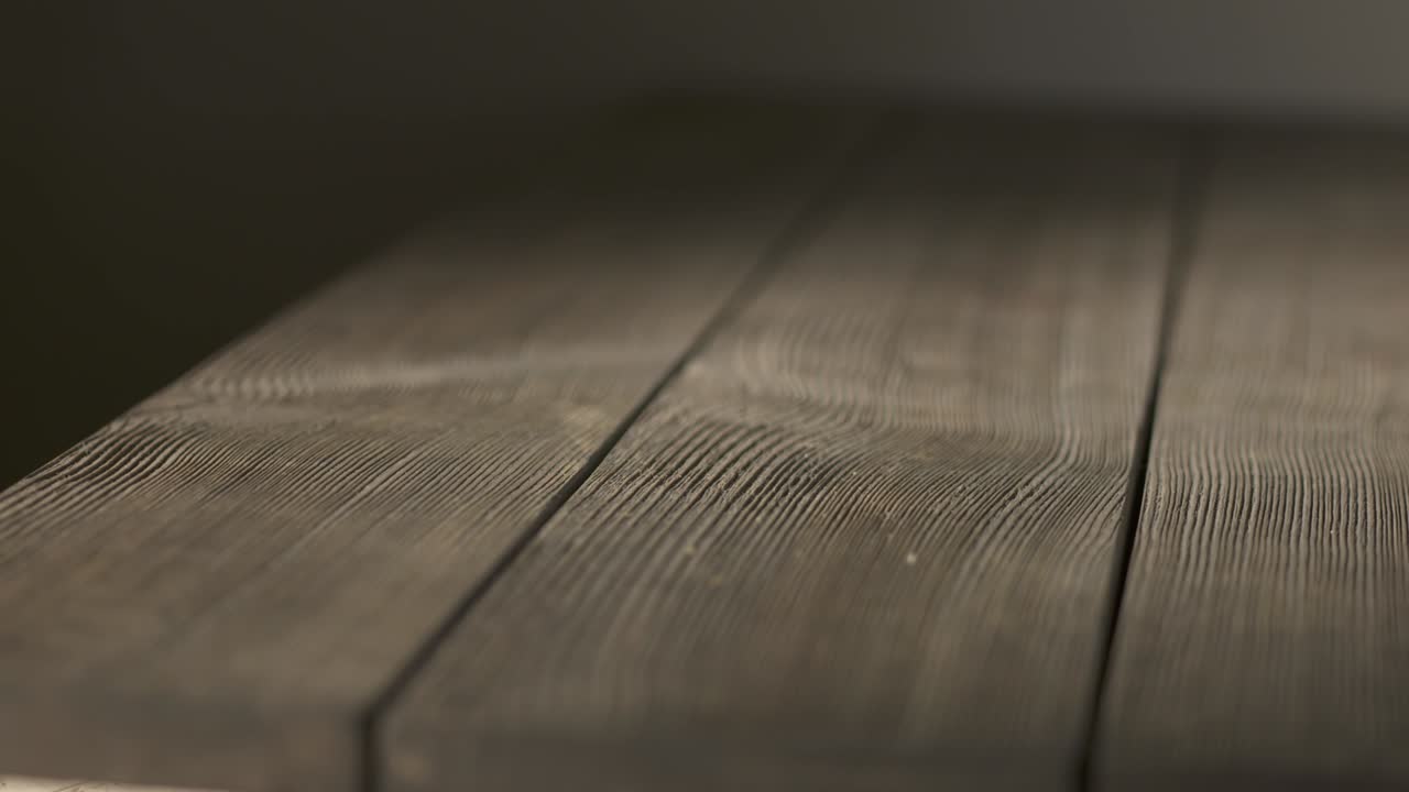 Empty rough wooden table in dark room. Aged textured wood looks rustic and old.