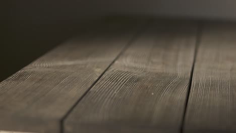 empty rough wooden table in dark room. aged textured wood looks rustic and old.