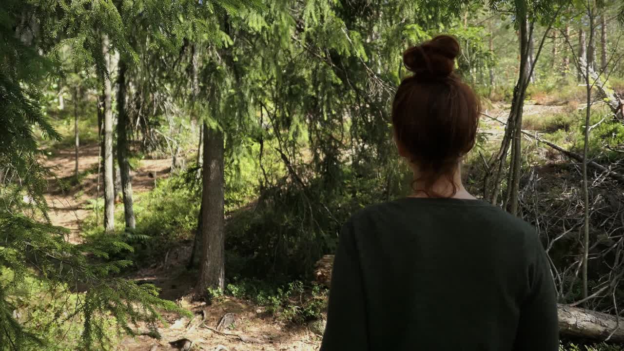 Woman walking in green forest path, calm nature walk, natural lifestyle, back view