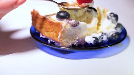pastel de mascarpone con arándanos y frambuesas, una mujer con una cuchara toma una baya