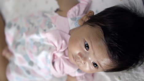 newborn asian baby in crib looking at camera.