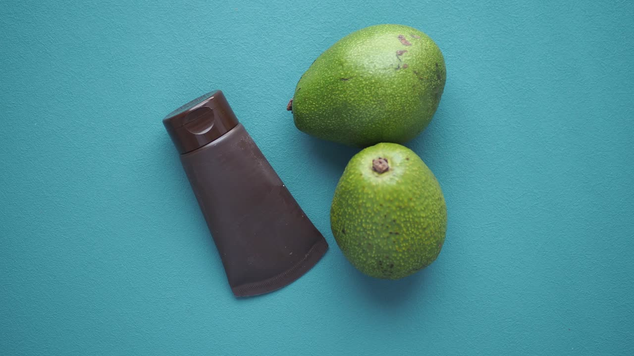aguacate y un tubo de crema sobre un fondo azul