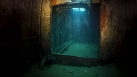 a scuba diver explores the inside of a sunken wreck while filming for a documentary