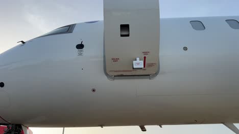 Pilot-closing-the-door-of-a-private-jet-from-inside,-wearing-a-cap-and-sunglasses