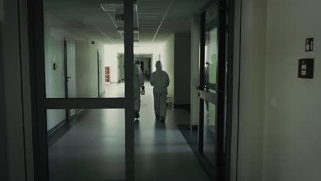 Video of workers in protective coveralls walk down the corridor