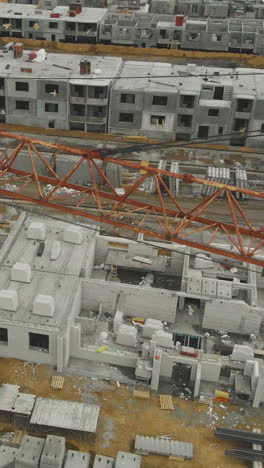 close rusty orange construction crane long boom against unfinished building with equipment on weekend bird eye view