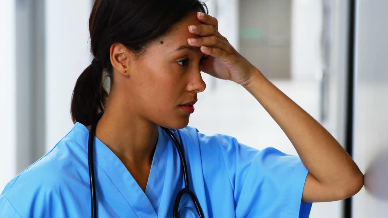 Tensed female doctor standing in corridor