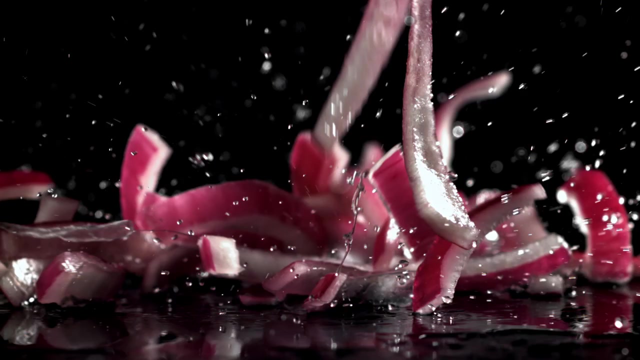 Fresh Red Onion Slices Splashing into Water in Slow Motion