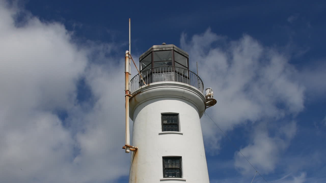 The lighthouse in Scarborough, North Yorkshire, England rises against a partly cloudy sky, with its lantern room and balcony visible in close-up time lapse