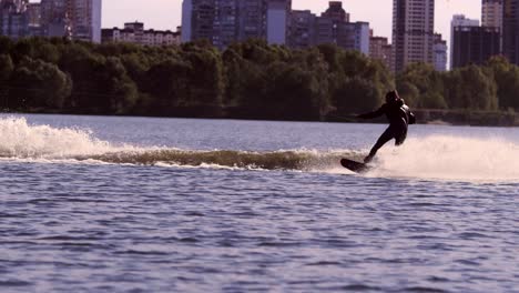 guy rushing along lake on water board in slow motion. extreme sport wakeboarding