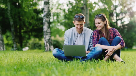 Begann-Mit-Einem-Laptop-Im-Park-Der-Mann-öffnet-Den-Laptop-Neben-Einer-Frau