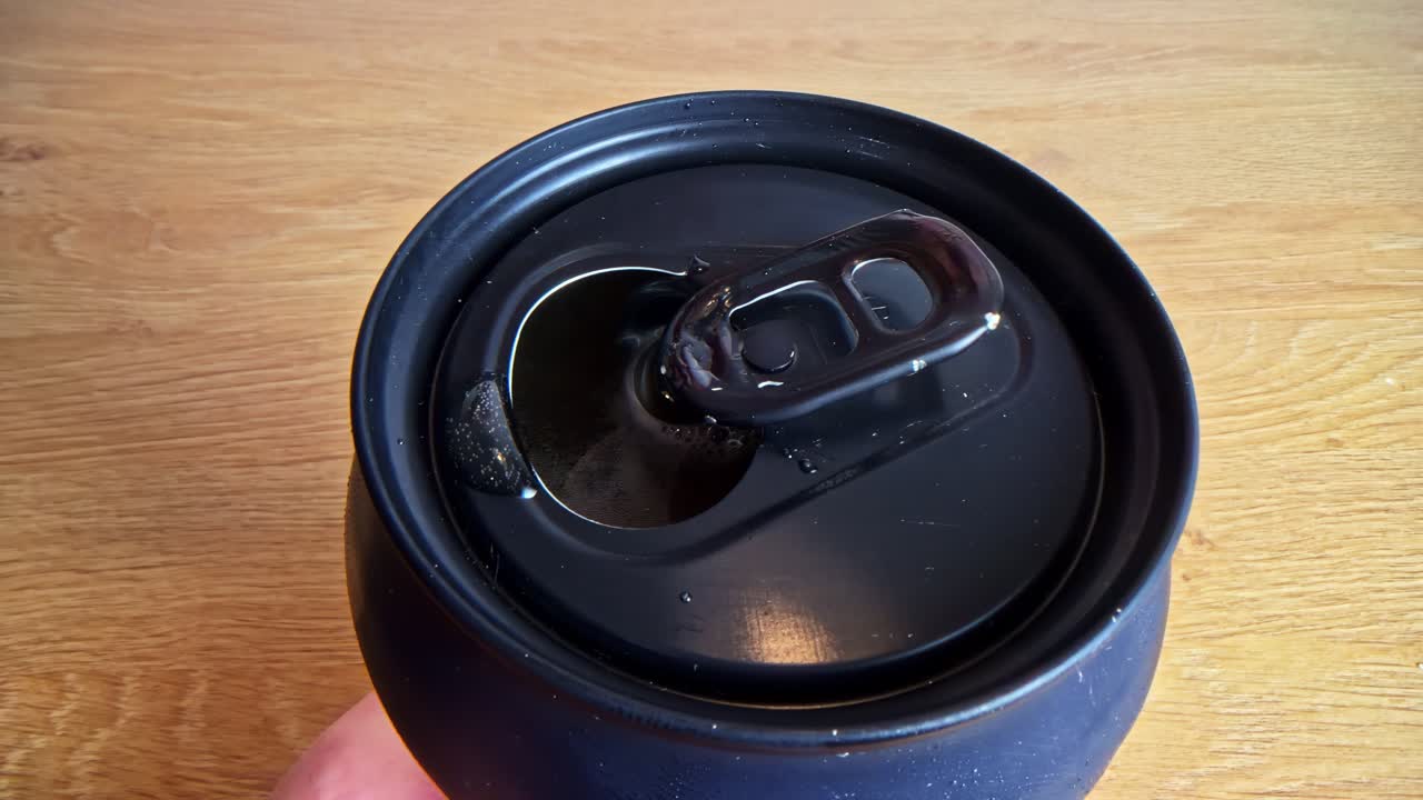 Hand opening a black soda can, anticipation and focus in a close-up view