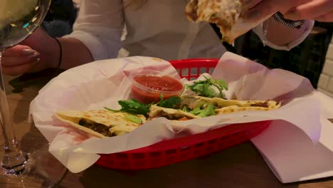 young attractive girl with a watch on hand tastes oriental food at the table where a glass of wine stands, slow motion in 4k