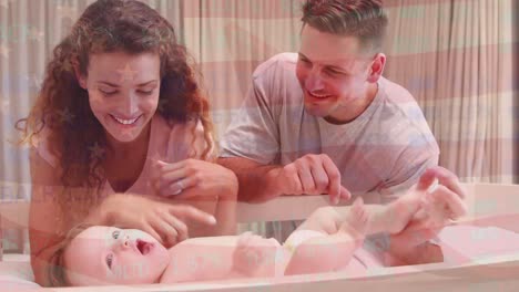 Animation-of-flag-of-usa-waving-over-happy-caucasian-parents-playing-with-baby