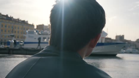 man looking at a boat in a city harbor