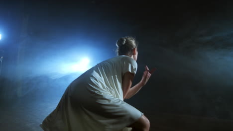 modern ballet dancing woman barefoot doing spins and pirouettes and dance steps standing on stage in smoke in slow motion. performance on stage.