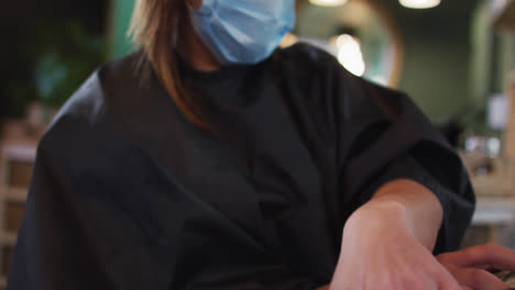 Female-customer-wearing-face-mask-choosing-from-hair-color-sample-chart-at-hair-salon