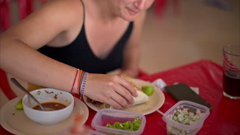 slow motion close up of a latin woman biting eating a barbacoa taco in a restaurant in mexico